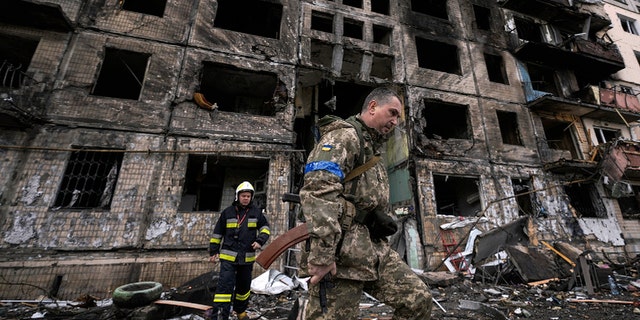 Ukrainian soldiers and firefighters inspect a destroyed building after a bomb attack in Kyiv, Ukraine, Monday, March 14, 2022. 