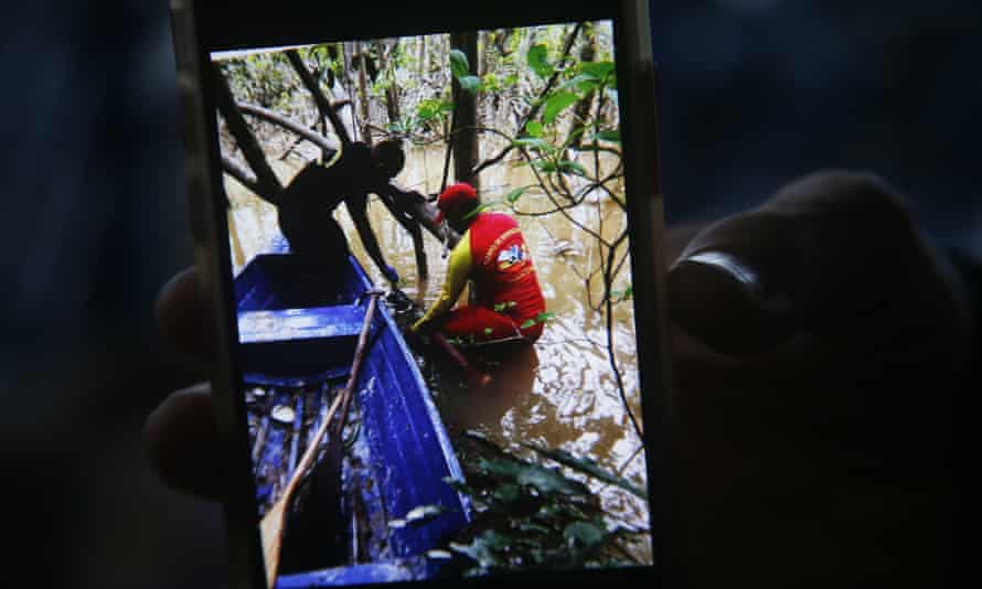 A firefighter holds a phone with a picture showing the moment a backpack was found while searching for Aboriginal expert Bruno Pereira and British journalist Dom Phillips