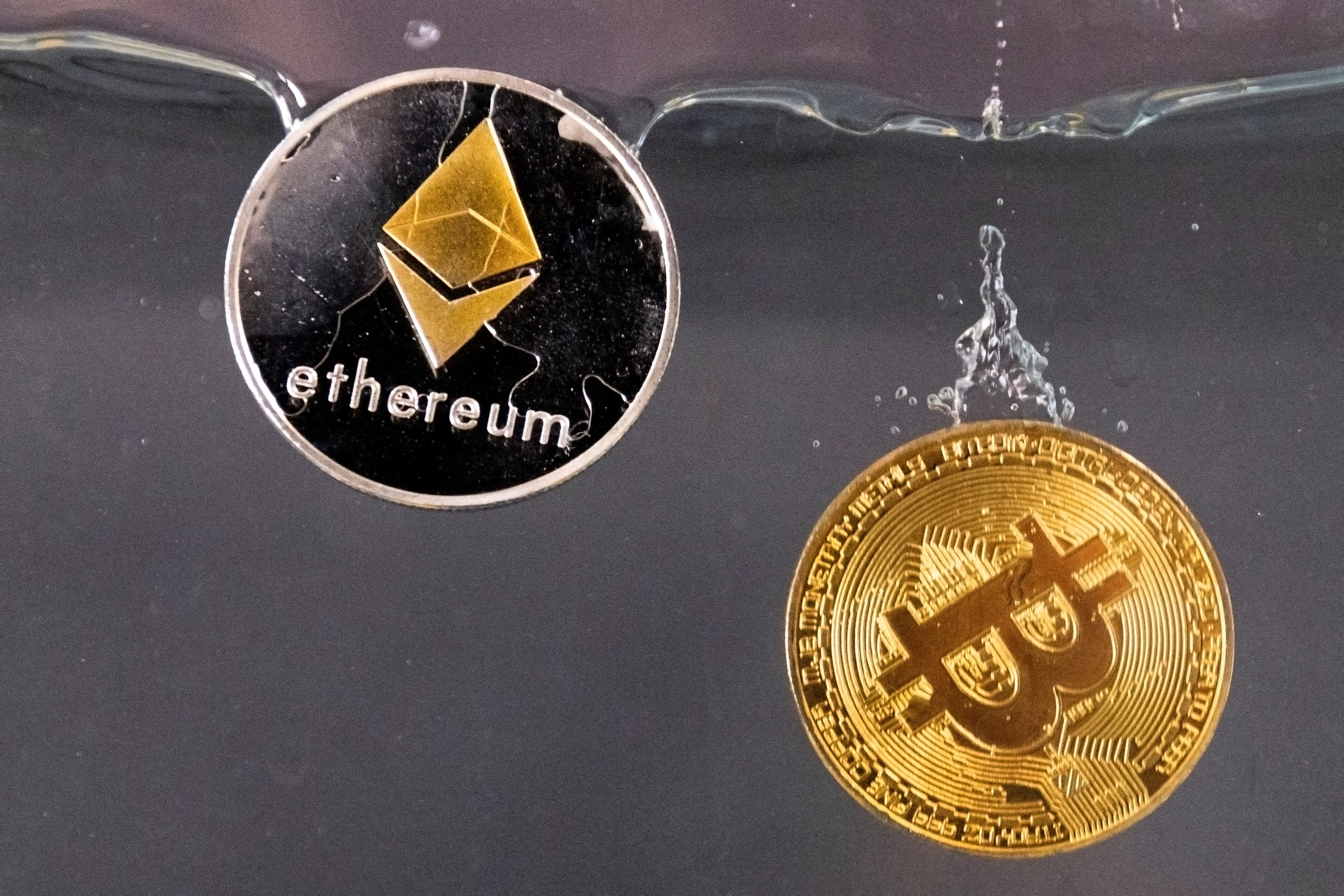 Commemorative Bitcoin and Ether tokens sink into water