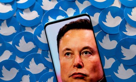 Image of Elon Musk on smartphone lying on printed Twitter logos