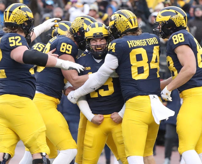Michigan football player Jake Moody, 13, celebrates with tight end Joel Honigford and other teammates after Moody scored the winning goal against Illinois at Michigan Stadium, Saturday, November 19, 2022.