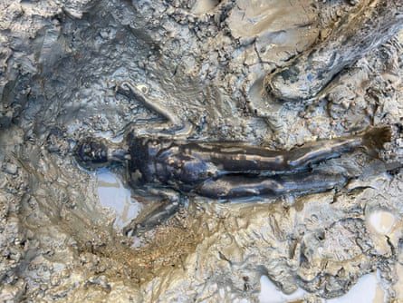 A well-preserved statue lying in the mud.